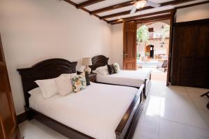 two beds in a room with white sheets at Hotel Plaza Colon - Granada Nicaragua in Granada +33 photos