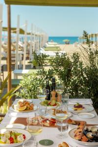 a table with plates of food and wine on the beach at Grand Hotel Imperiale in Forte dei Marmi