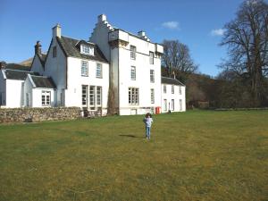 a young boy standing in a field in front of a large house at Inverawe Cottages in Taynuilt