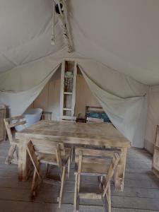 a wooden table and chairs in a tent at Dworska Polana in Szteklin +4 photos