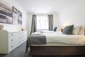 a white bedroom with a large bed and a dresser at Spacious 6BR Cardiff House w/ Free Parking in Cardiff