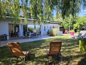 two chairs sitting in the grass under a tree at La parenthèse du lac in Bevaix