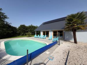 a swimming pool with blue chairs and a house at Gîte Ker Koad in Pluduno