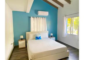 a bedroom with a white bed with a blue wall at Blue Sail Apartments in Simpson Bay +238 photos