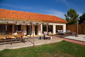 a house with a deck with tables and chairs at Goodmuda in Grândola