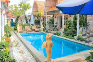 a pool with a statue next to a house at The Box Paradise Bungalow in Nusa Penida