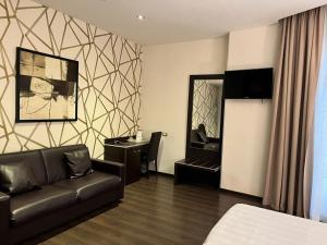 a hotel room with a couch and a desk and a mirror at Hotel Infinity San Pietro in Rome