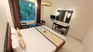 a bedroom with a bed and a desk and a window at Hotel Garden Panvel - Near Navi Mumbai Airport in Navi Mumbai