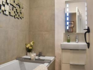 a bathroom with a sink and a mirror and a tub at Granary Cottage in Kirkby Malham