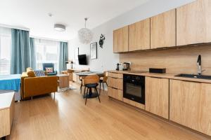 a kitchen with wooden cabinets and a living room at Golden Apartments in Gdańsk