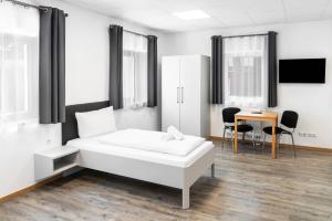 a white room with a bed and a table at Rote Villa Füssen in Füssen +14 photos