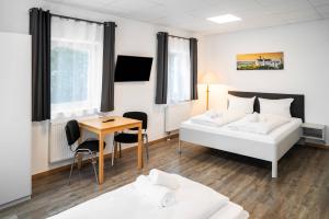 a room with two beds and a table and a desk at Rote Villa Füssen in Füssen