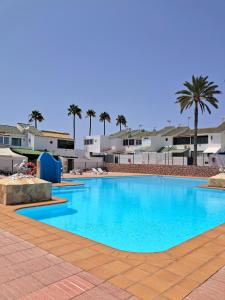 a large blue swimming pool with palm trees in the background at Villa Maria Maspalomas Gran Canaria in Maspalomas