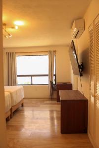 a bedroom with a bed and a tv and a window at Villa del Mar in Cancún