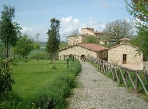 a stone building in a field next to a fence at Residenza Il Platano Fortilizio di Campiglia in Rapolano Terme