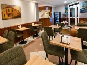 a restaurant with wooden tables and green chairs at Hôtel des Bains 24h 7j Paris centre à 10 min in Maisons-Alfort