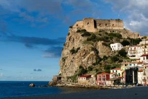 a castle on top of a mountain next to the ocean at Aura in Scilla