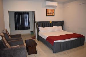 a bedroom with a bed with a chair and a couch at Royal Residency in Vākalapūdi