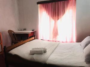 a bed with two towels on it in front of a window at Sapphire Homestay in Palle Deltota
