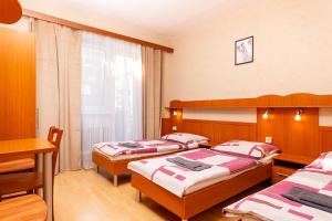a bedroom with three beds and a table and a window at Penzión ORION in Prievidza +23 photos