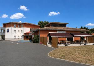 a building with a patio and a building at Hôtel Restaurant Akena Bordeaux Sud - La Brède in La Brede