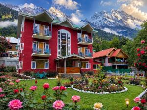 a large red building with flowers in a garden at Hotel Gulsar pahalgam in Pahalgām