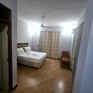 a bedroom with a white bed and a wooden floor at Paradiso Apartments in Dar es Salaam