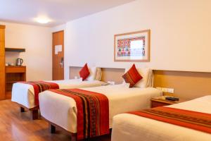 a hotel room with three beds with red and white blankets at San Agustin Plaza in Cusco