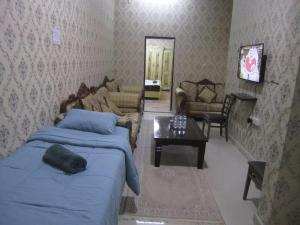 a bedroom with a bed and a couch and a table at العين الهيلي مصباح بيت 2 in Al Ain