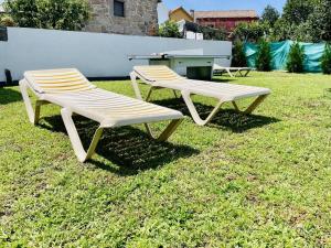 two white benches sitting on the grass in a yard at Villa 1-12 Personas a 3 minutos de las playas in Villanueva de Arosa