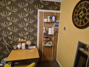 a room with a table and a clock on a wall at Levens Terrace, Barrow Spa Therapy in Barrow in Furness