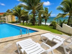 two white chairs and a swimming pool with the ocean at Premium Apartment with Ocean View in Santiago