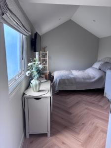 a bedroom with a bed and a vase of flowers on a table at Riverhill in Abersoch