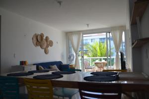 a dining room with a table with chairs and a couch at #204 Corais de Búzios - Apartamento à beira-mar na enseada de Búzios in Nísia Floresta