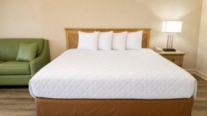 a bedroom with a bed and a green chair at Royal Inn Hotel in Royal Palm Beach