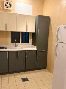 a kitchen with green cabinets and a white refrigerator at الارجان للشقق المفروشة in Al Nairyah