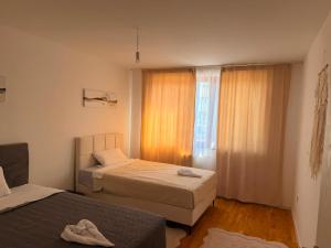 a small bedroom with two beds and a window at Elite Suites - Vogošća in Vogošća