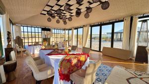 a dining room with a table and chairs and windows at Yes We Camp Agafay Luxury Khaïma & Restaurant - Spa in El Karia