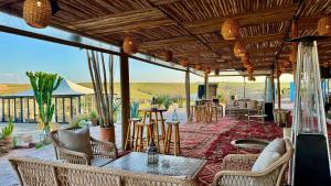 a patio with chairs and tables and a living room at Yes We Camp Agafay Luxury Khaïma & Restaurant - Spa in El Karia