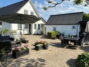 a patio with a table and an umbrella in front of a house at Hulen, Lundeledsvej 5 in Lund