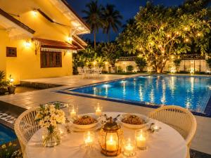 Ein Tisch mit Kerzen und Tellern mit Essen neben einem Pool in der Unterkunft sunvilla in Negombo