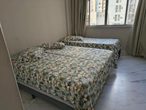 a bed with two pillows on it in a bedroom at Castanheiras,perto de tudo,Internet,cadeiras,cooler e guarda sol in Guarapari