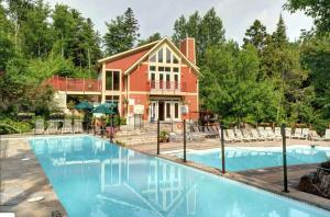 a home with a swimming pool in front of a house at Tremblant Les Eaux by Rendez-Vous Mont-Tremblant in Mont-Tremblant