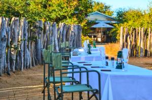 a group of tables with green chairs and a fence at Omulunga Bush Camp in Ruacana