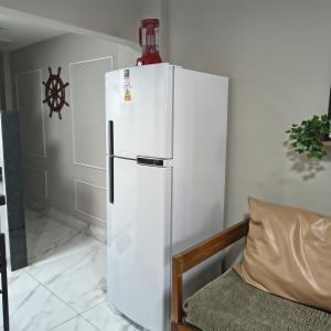 a white refrigerator with a bottle on top of it at Castanheiras,perto de tudo,Internet,cadeiras,cooler e guarda sol in Guarapari