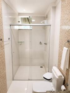 a white bathroom with a shower and a toilet at Hotel Vista Bela in Itamaraju