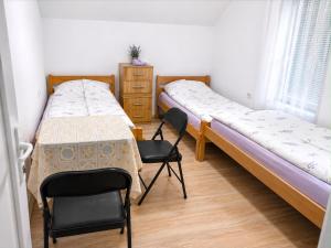 two beds in a room with chairs and a table at Guest House Ulnika in Vusanje