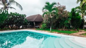 a swimming pool in front of a house with palm trees at Villa Amani in Malindi