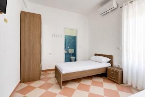 a white bedroom with a bed and a mirror at South Hotel Berat in Uznovë
