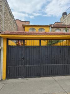 a black garage door in front of a yellow building at Casa de los Sauces in Toluca